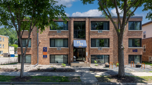 Front entrance of brick exterior building with three floors of unit windows.